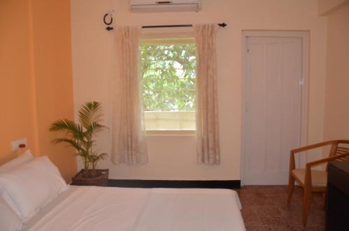 a bedroom with a white bed and a window at Hotel Ferreira Resort in Lonavala