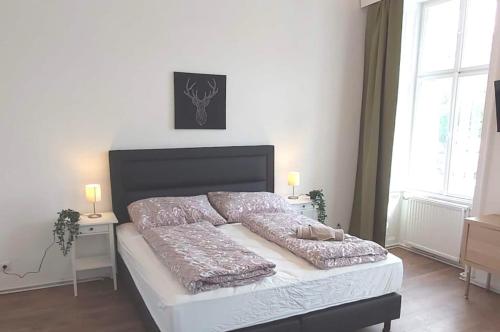 un lit dans une chambre avec deux tables de nuit et deux fenêtres dans l'établissement Cozy new apartment near Hannovermarkt, à Vienne