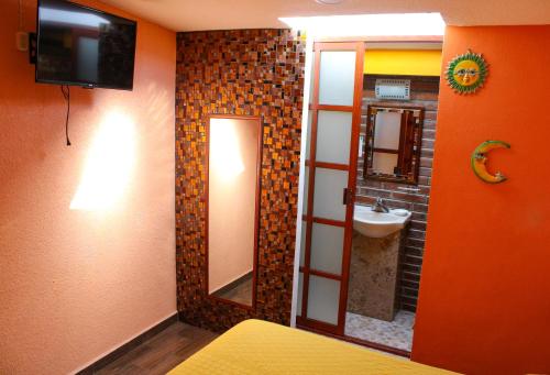 a bathroom with a sink and a mirror and a television at Hospedaje Ensueño in Zacatlán