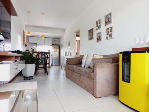 a living room with a brown couch and a kitchen at Verano Residencial in Guarajuba