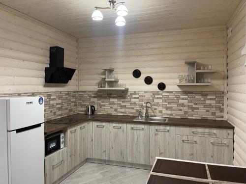 a kitchen with wooden cabinets and a white refrigerator at Villa Затишна de luxe in Mykulychyn