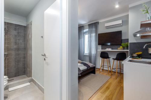 a bathroom with a walk in shower next to a kitchen at Adria Square Studios in Rijeka