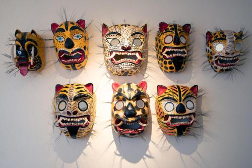 a group of masks hanging on a wall at William Hotel Boutique De Diseño in Taxco de Alarcón
