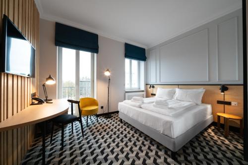 ein Hotelzimmer mit einem Bett, einem Schreibtisch und Fenstern in der Unterkunft Hotel Tulip Residences Warsaw Targowa in Warschau