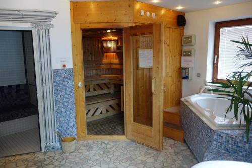 a bathroom with a bath tub and a wooden closet at Edelsteinhotel Guniwirt in Krakaudorf