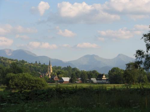 a village with mountains in the background and a church at Pokoje Pod Bocianem in Chochołów