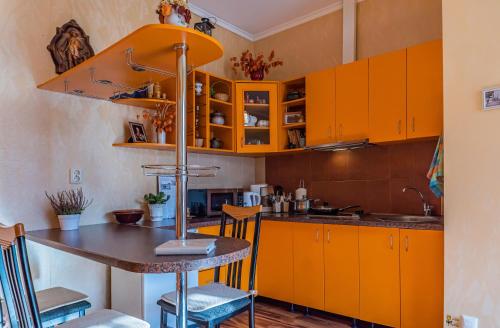 a kitchen with orange cabinets and a table with chairs at Pālena apartamenti in Tērvete