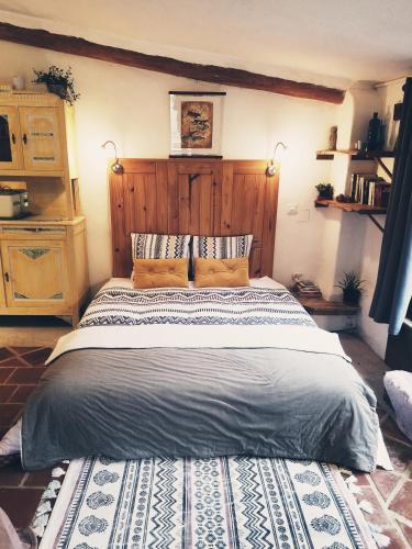Un dormitorio con una cama grande con cabecero de madera. en Petit Gîte TARA avec SPA - Ariege Pyrénées, en Péreille