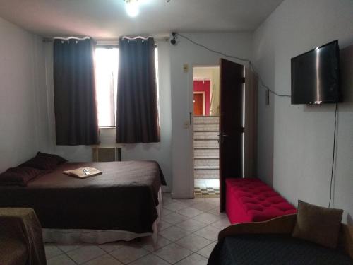 a bedroom with a bed and a couch and a television at Apto flat Antônio in Campos dos Goytacazes