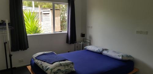 um quarto com uma cama azul e uma janela em Affordable, Spacious, Bright, Warm, Unit in Central Whangarei em Whangarei