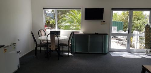 Habitación con mesa, sillas y TV. en Affordable, Spacious, Bright, Warm, Unit in Central Whangarei, en Whangarei