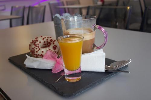 a glass of orange juice and a doughnut on a black tray at Hotel Boutique Albussanluis in Muriedas