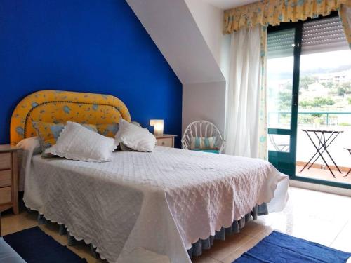 sypialnia z łóżkiem z niebieską ścianą w obiekcie Precioso ático con vistas a pie de playa w mieście Sanxenxo