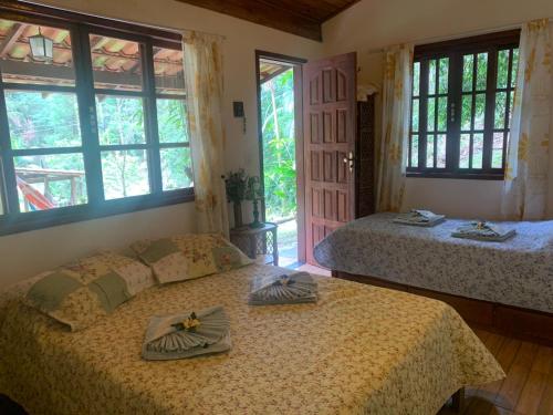 2 camas en un dormitorio con ventanas y puerta en Chalé Hakuna Matata en Lumiar