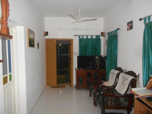 a living room with a tv and chairs and a tvicterictericter at Heavenly Homestay in Cochin