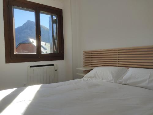a bedroom with a white bed and a window at Bozocarro Descanso in Sallent de Gállego