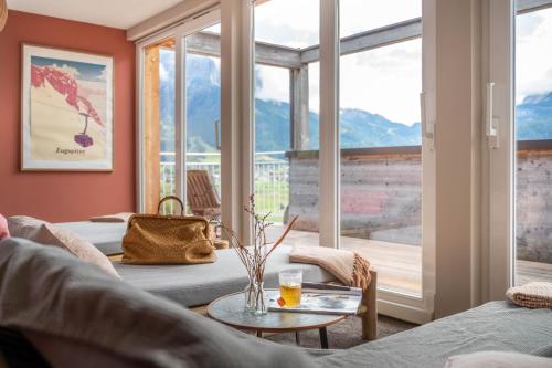 a living room with a table and a large window at Boutique Hotel Bellevue Lermoos in Lermoos