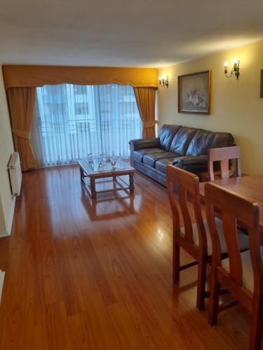 sala de estar con sofá de cuero y mesa en Departamento Temuco Thiers en Temuco