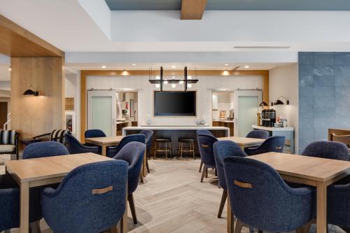a dining room with tables and chairs and a flat screen tv at Staybridge Suites - Iowa City - Coralville by IHG in Coralville