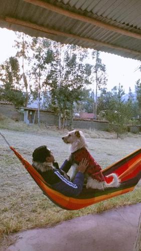 a man and a dog sitting in a hammock at Tony's House Eco Hostel in Huaraz