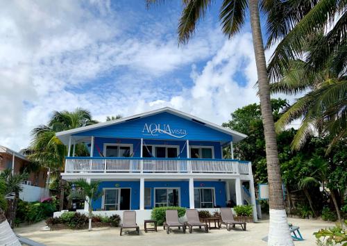 a blue house with a balcony and palm trees at Aqua Vista in San Pedro