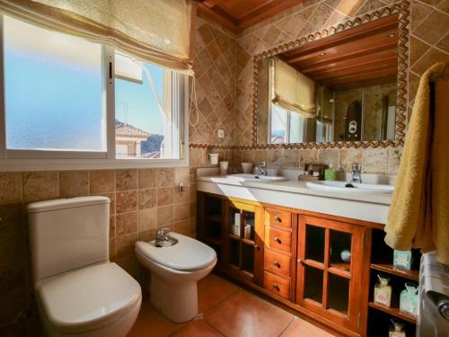 a bathroom with a toilet and two sinks and a window at Apartamentos Turísticos Tronca Luxury in Granada