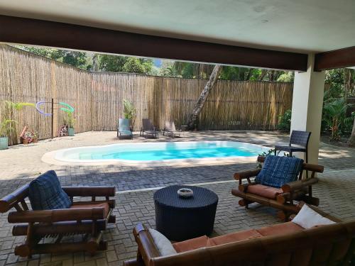 a patio with a swimming pool with chairs and a table at Hona Beach Hotel in Dominical