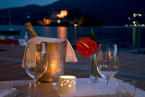a table with wine glasses and a bottle and a rose at Hotel San Rocco in Orta San Giulio