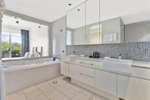 a white bathroom with a tub and a sink at Bale Luxury Resort - Holiday Management in Kingscliff