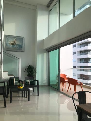 a living room with glass doors and chairs at Apartamentos Cartagena Marbella Suite in Cartagena de Indias