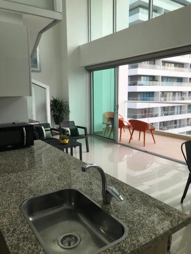 a kitchen with a sink and a living room at Apartamentos Cartagena Marbella Suite in Cartagena de Indias