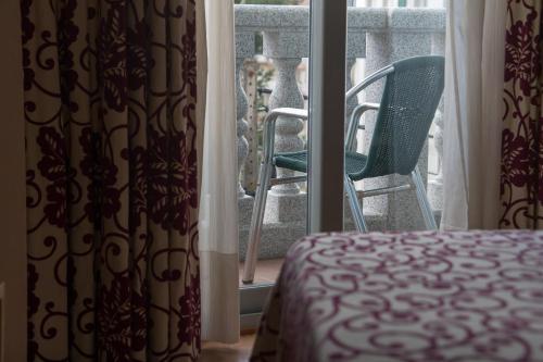a room with a bed and a chair in front of a window at Pontus Veteris in Sanxenxo
