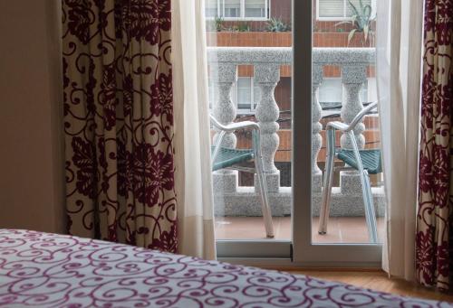 a bedroom with a window with a view of a balcony at Pontus Veteris in Sanxenxo
