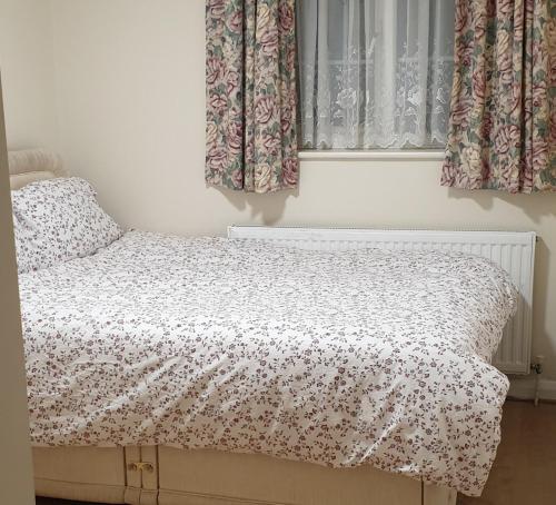 a bed in a bedroom with curtains and a window at Lime House in Hayes