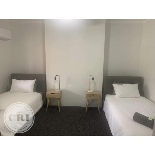 a room with two beds and two tables with lamps at Criterion Hotel Grenfell in Grenfell