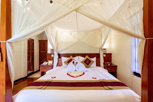 a bedroom with a bed with a canopy at Lumbung Sari Ubud Hotel in Ubud