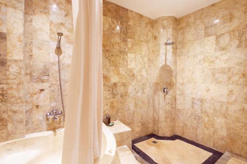 a bathroom with a shower and a bath tub at Lumbung Sari Ubud Hotel in Ubud