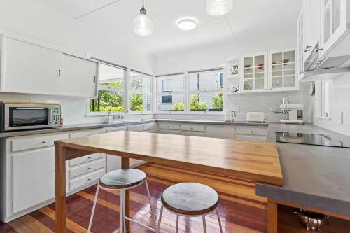 a kitchen with white cabinets and a wooden table at Artist's Cottage - Cosy Home in Quiet Leafy Street in Toowoomba