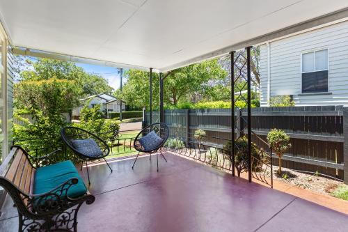 a screened porch with three chairs and a fence at Artist's Cottage - Cosy Home in Quiet Leafy Street in Toowoomba