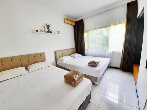 two beds in a room with a window at Vila Batu Bale-Bale in Batu