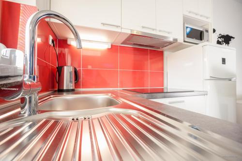 a kitchen with a sink and a red wall at Apartment Indigo in Zadar