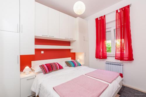 a bedroom with a white bed with red accents at Apartment Indigo in Zadar