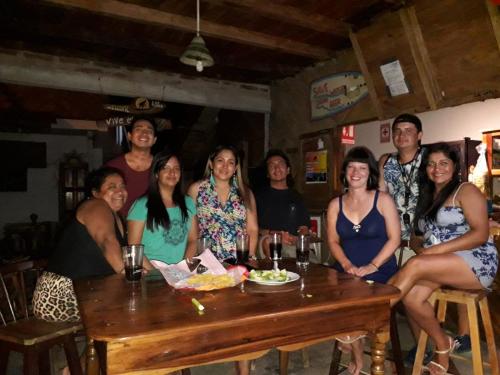 a group of people sitting around a wooden table at Hostal Mirada al Mar in Las Tunas