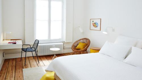 1 dormitorio blanco con 1 cama, mesa y sillas en Hotel des Galeries, en Bruselas