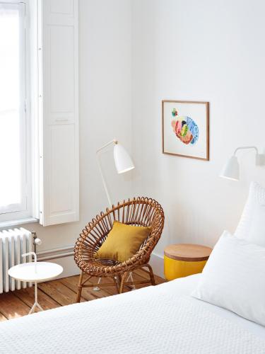 a bedroom with a rattan chair and a bed at Hotel des Galeries in Brussels