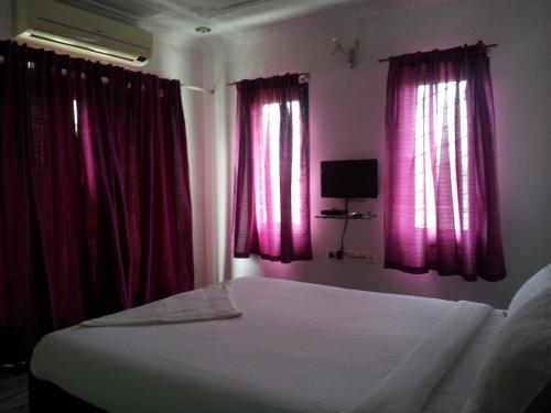 a bedroom with pink curtains and a bed and a television at Roshini Serviced Apartments in Chennai
