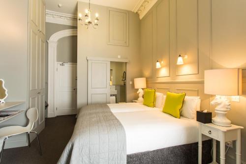 a bedroom with a large white bed with yellow pillows at Georgian House Hotel in London