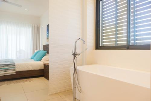 a bathroom with a bath tub and a bed at Cap Ouest by Horizon Holidays in Flic-en-Flac