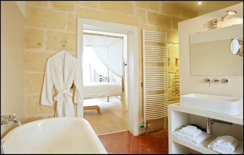 une salle de bain avec une baignoire blanche et un lavabo dans l'établissement La Maison Rouge d'Uzes B&B, à Uzès