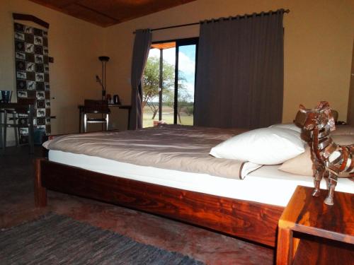 a bedroom with a large bed with a window at Ovita Wildlife Restcamp in Okazize